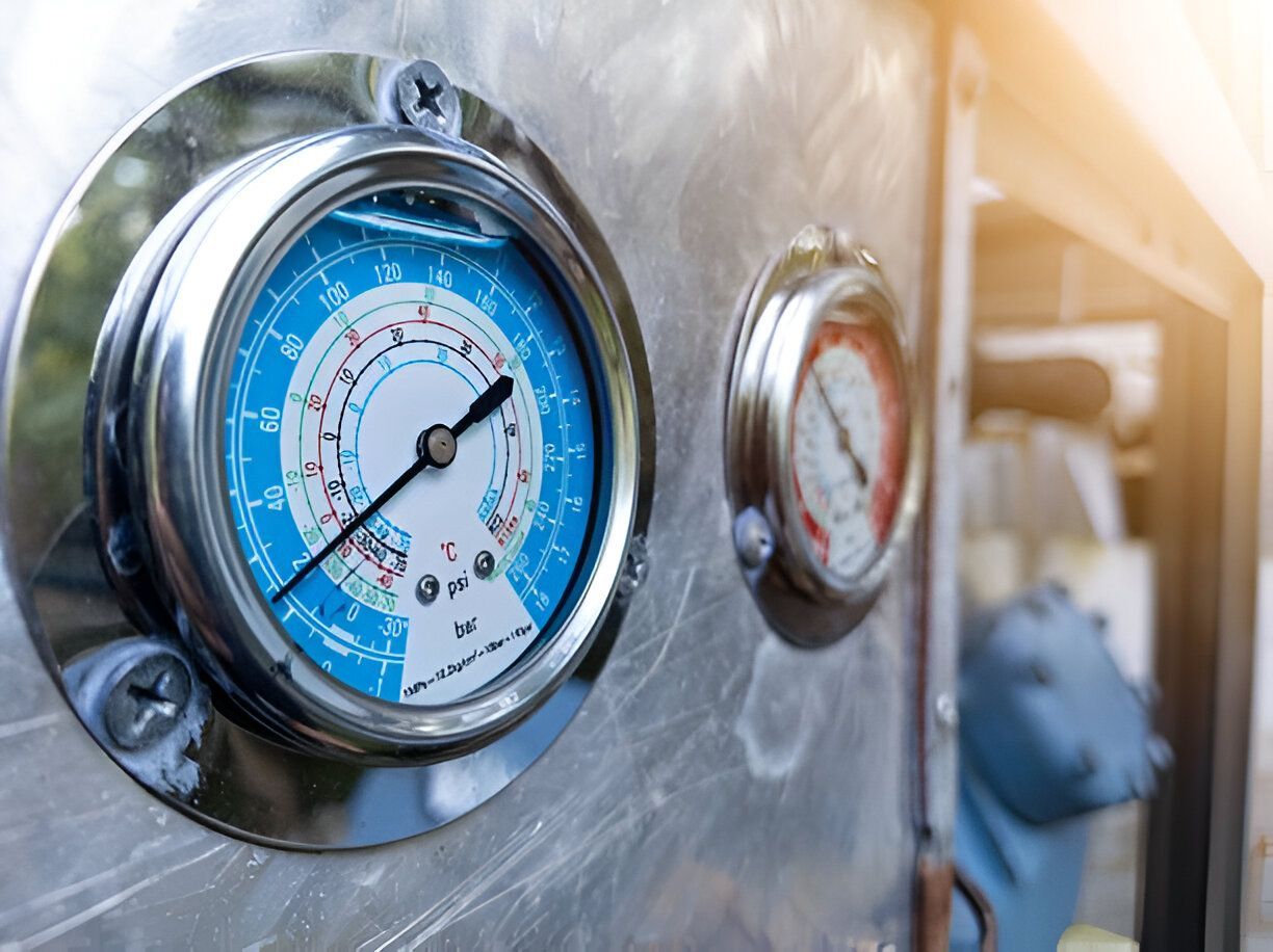 Blue and white pressure gauge on a silver surface, indicating pressure with a black needle.