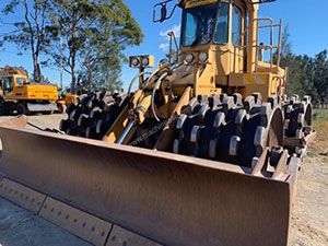 A yellow bulldozer is parked in a dirt lot.