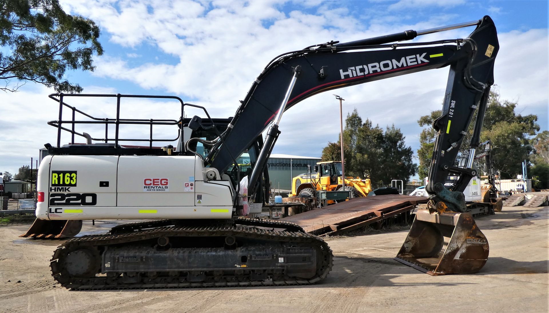 A large excavator is parked in a dirt lot.
