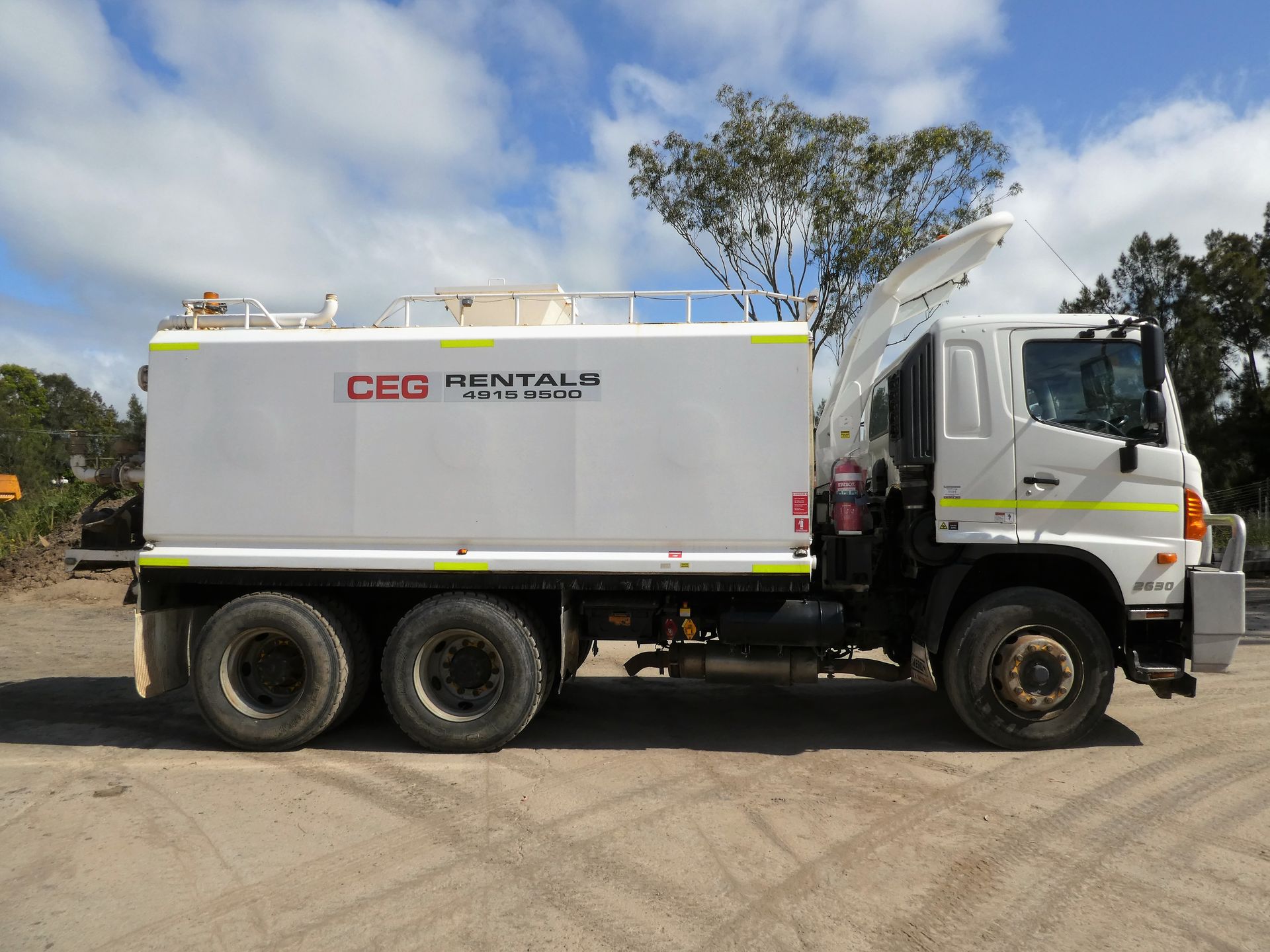A white cgg rental truck is parked in a dirt lot