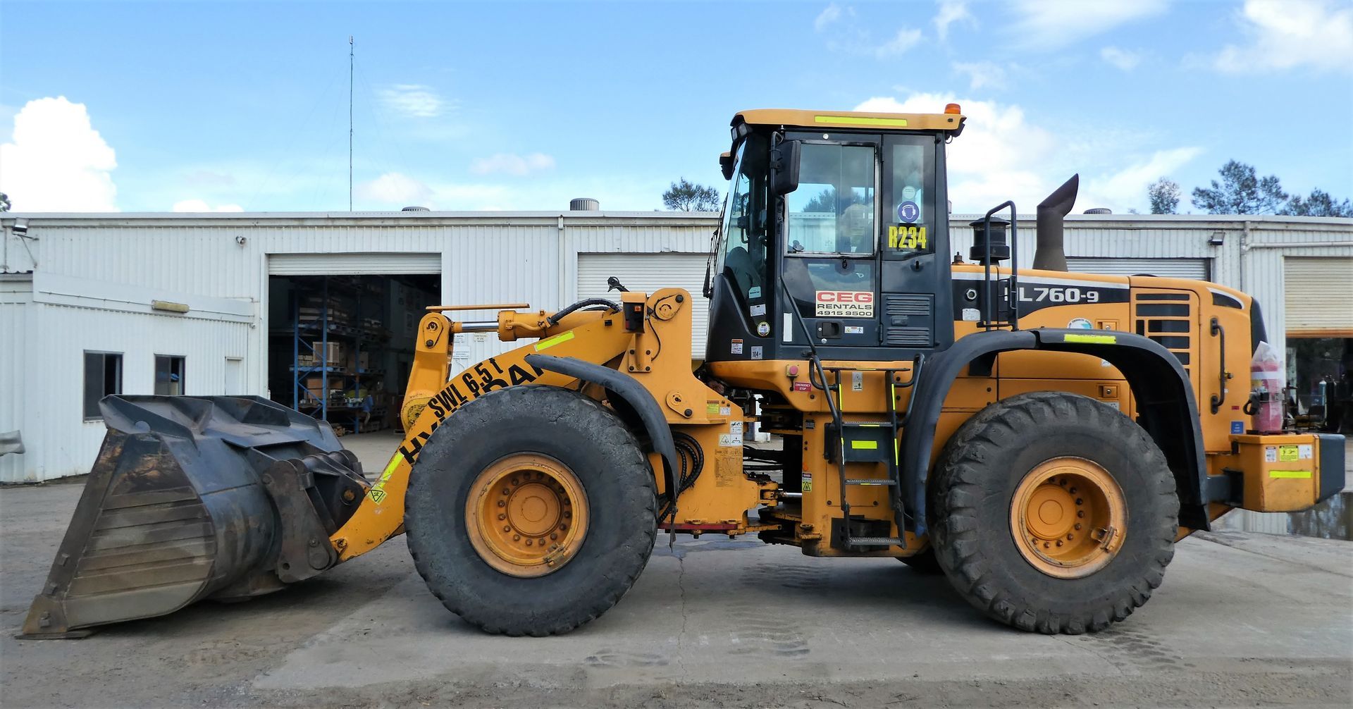 A yellow wheel loader is parked in front of a building.