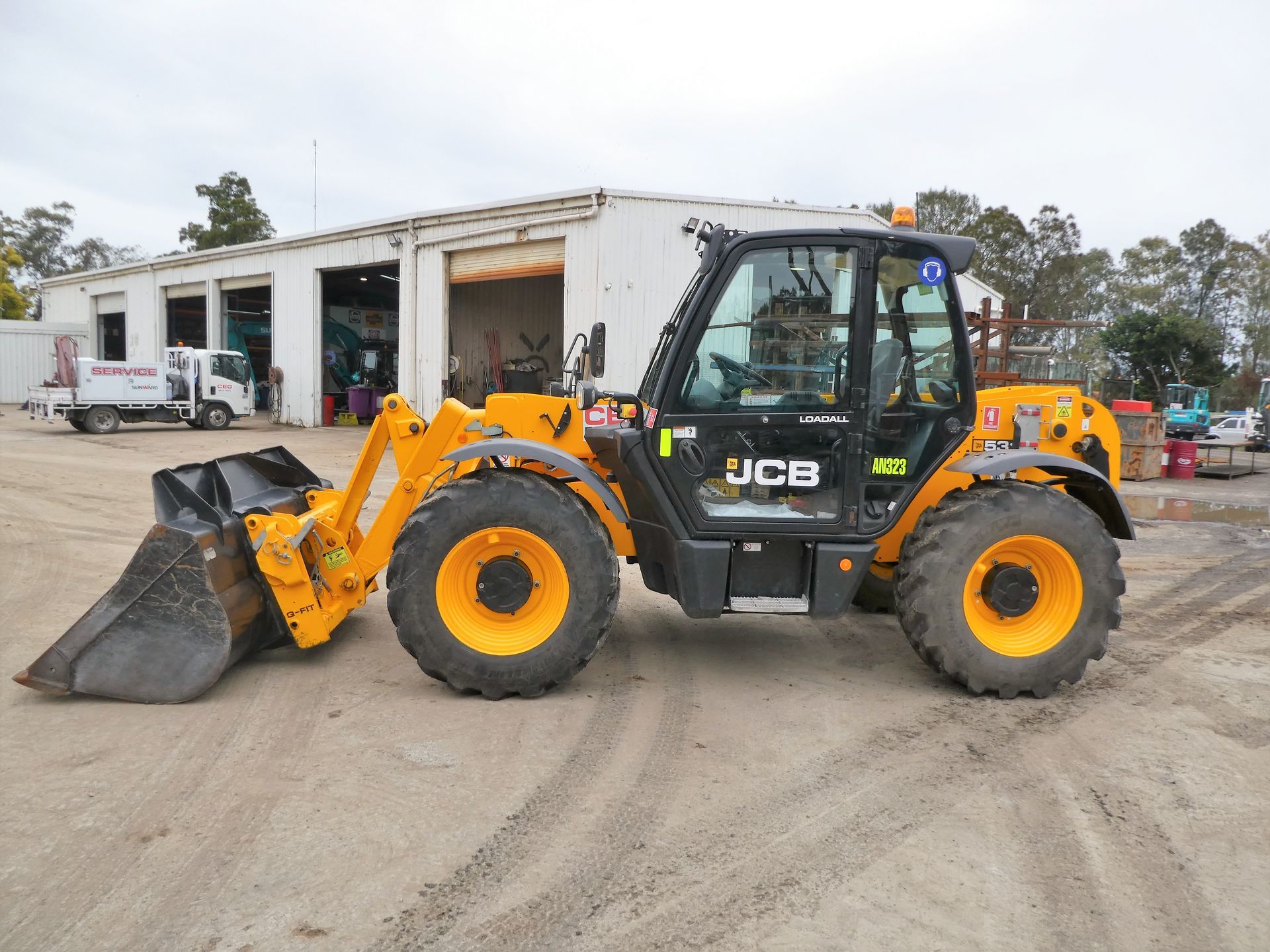 A yellow and black jcb tractor is parked in front of a building.