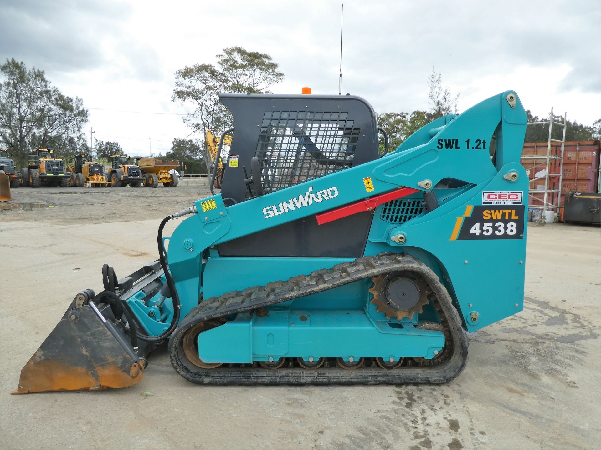 A blue and black skid steer is parked in a parking lot.