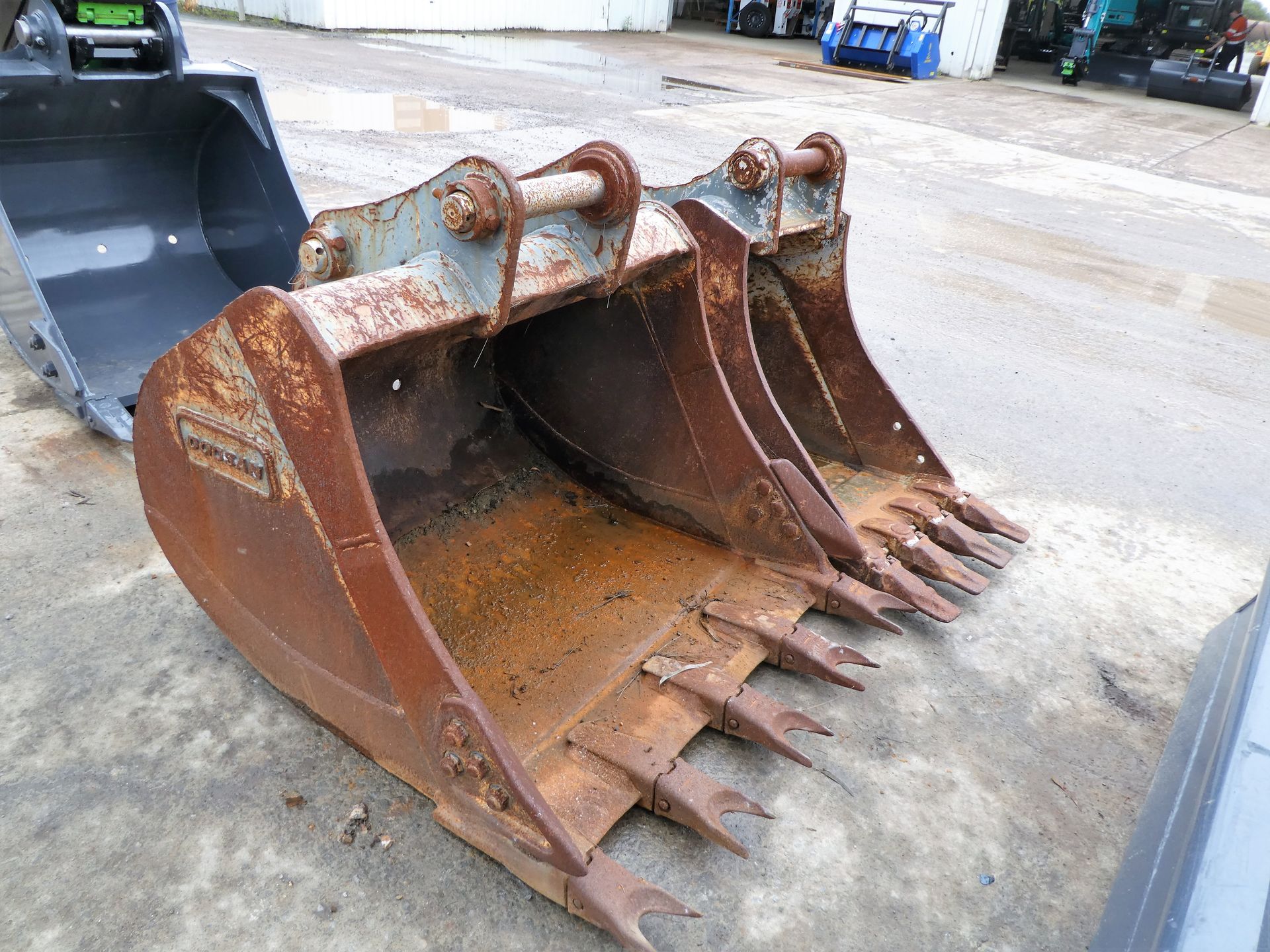 A rusty bucket is sitting on the ground next to a black bucket.