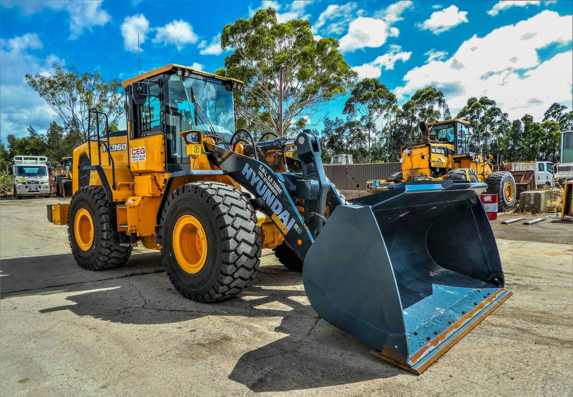 A yellow hyundai wheel loader is parked in a parking lot.