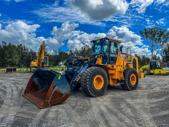 A bulldozer with a large bucket is parked in a dirt lot.
