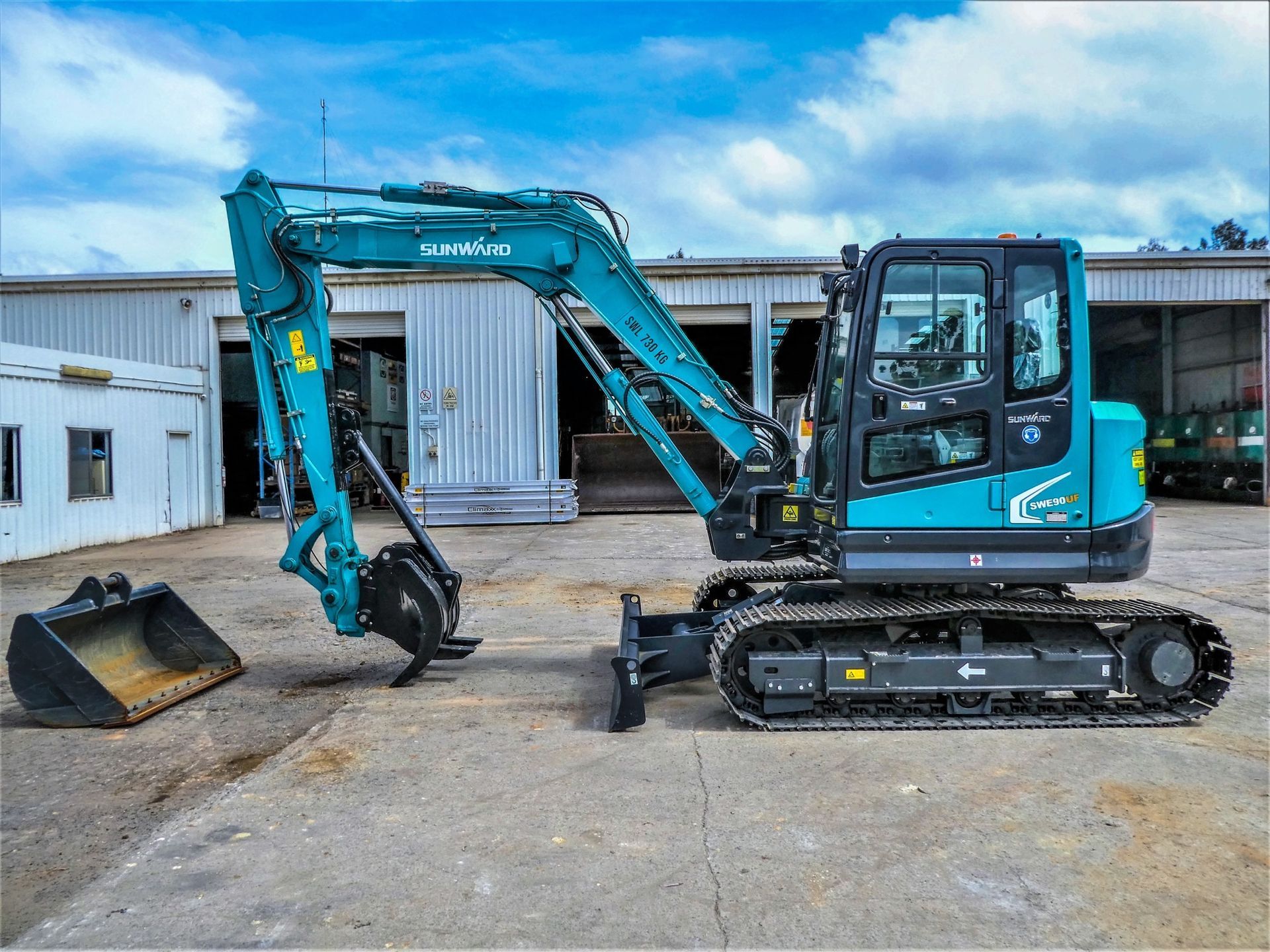 A blue excavator is parked in front of a building.