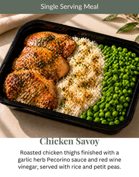 Single-serving chicken dinner with peas, rice, and sauce in a black tray