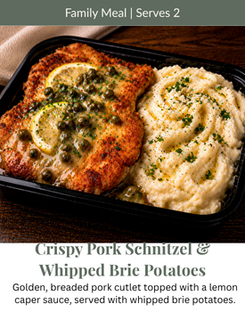 A meal of breaded pork schnitzel with lemon-caper sauce and whipped brie potatoes in a black container.