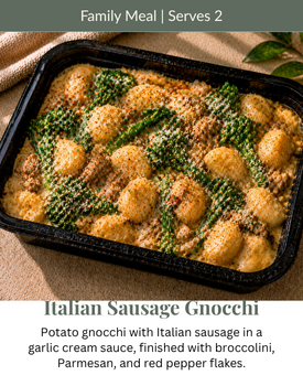 Italian sausage gnocchi in a black tray, topped with broccoli and parmesan on a family meal card