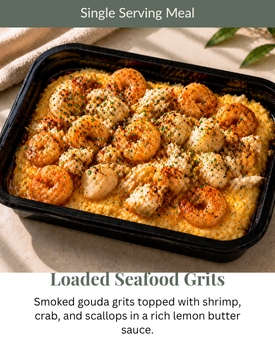 Loaded seafood grits in a black tray with shrimp, crab, and scallops in butter sauce.