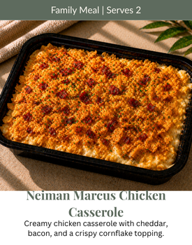 Neiman Marcus chicken casserole in a black tray, topped with golden breadcrumbs on a table.