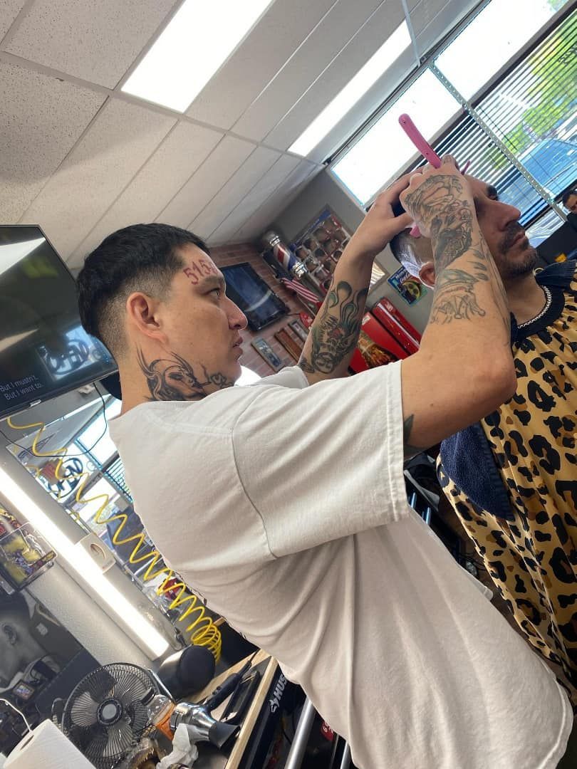 A man is getting his hair cut by a barber in a barber shop.
