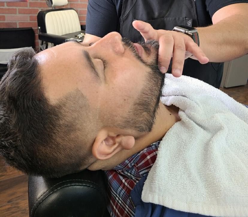 A man is getting his beard shaved by a barber