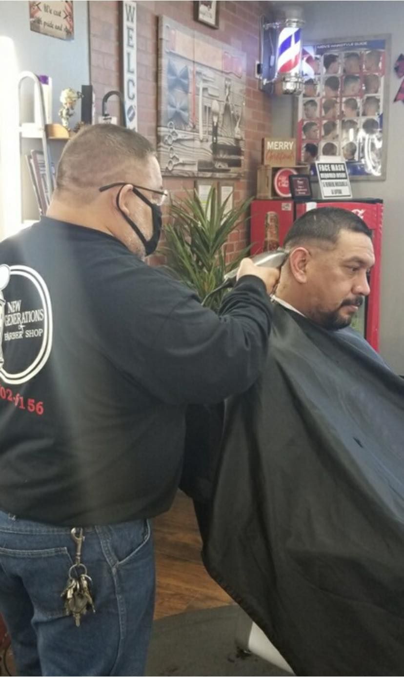 A man is getting his hair cut by a barber in a barber shop.