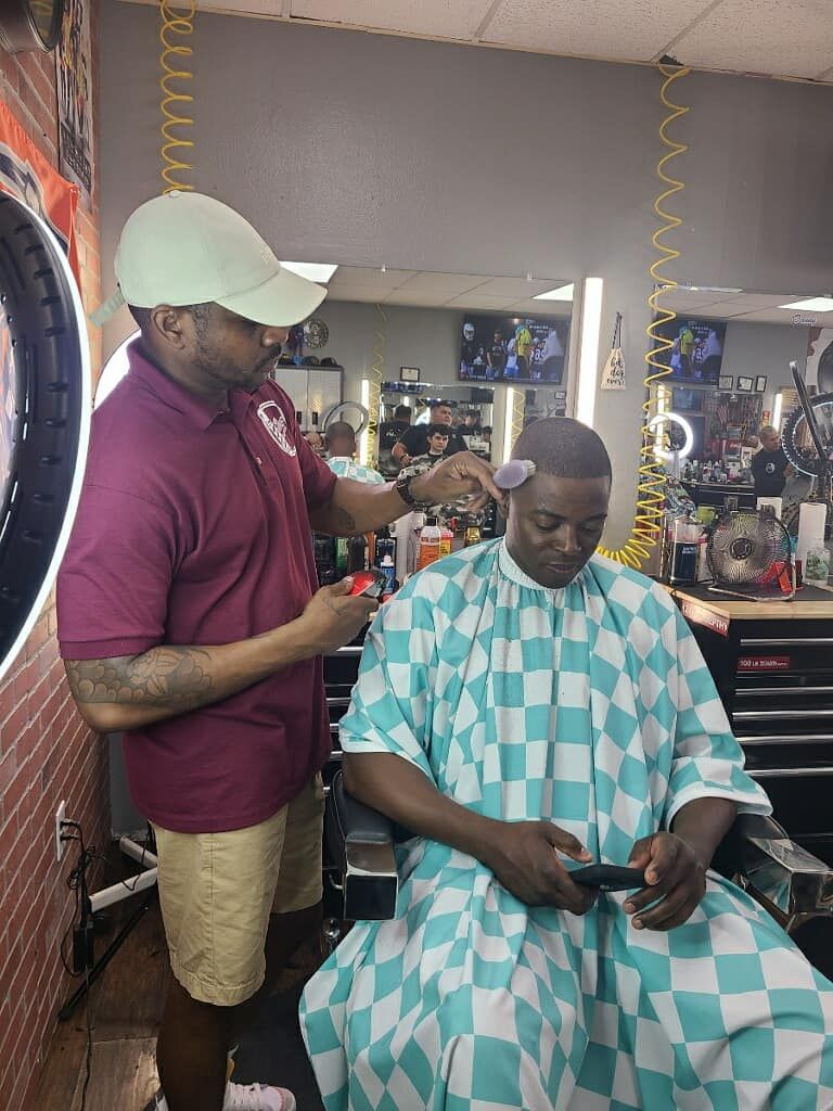 A man is getting his hair cut by a barber in a barber shop.