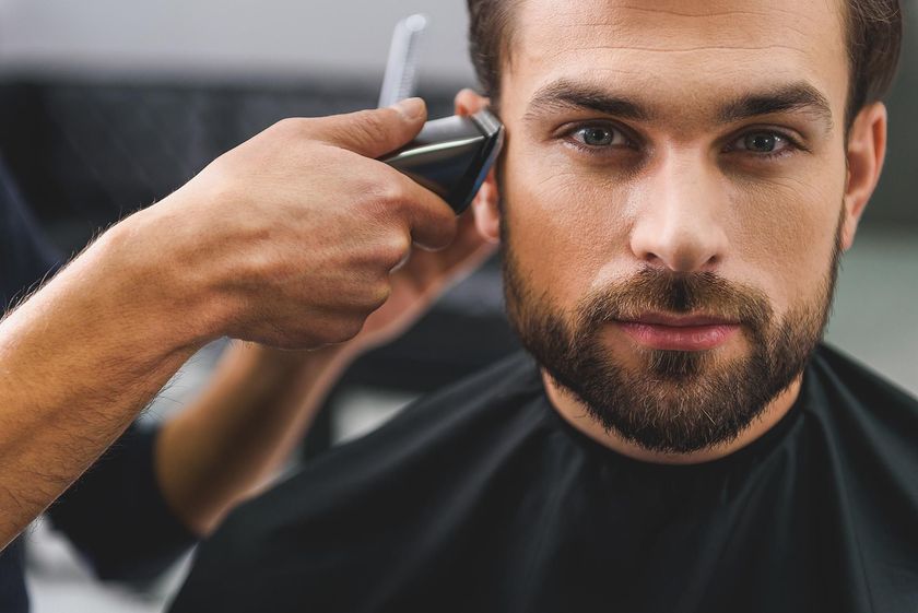 A man is getting his hair cut at a barber shop.