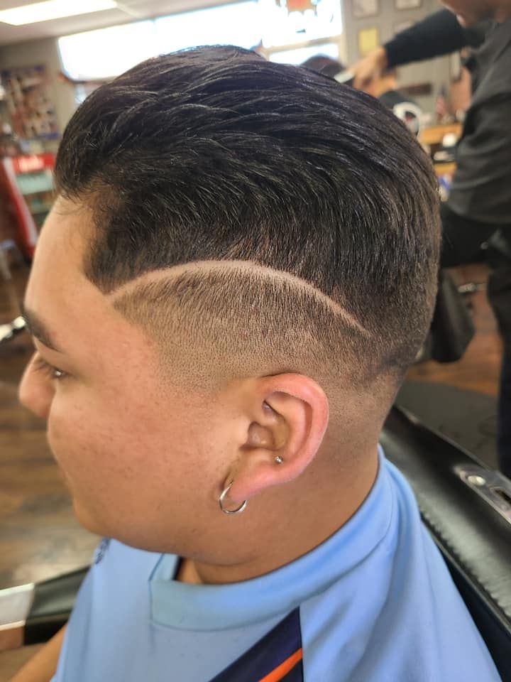 A young man is getting his hair cut at a barber shop.