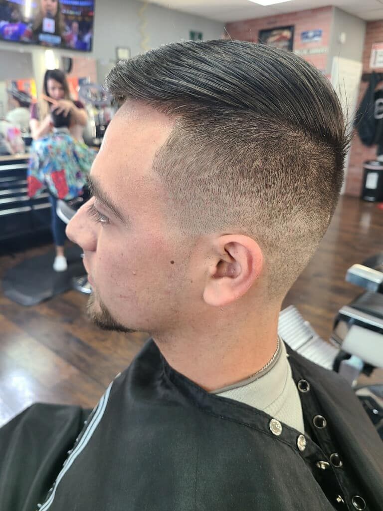 A man is getting his hair cut at a barber shop.