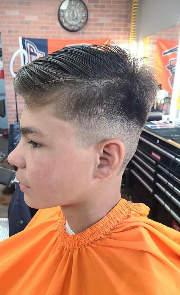 A young boy is getting his hair cut at a barber shop.
