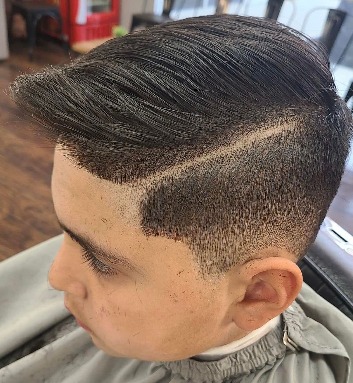 A young man is getting his hair cut at a barber shop.