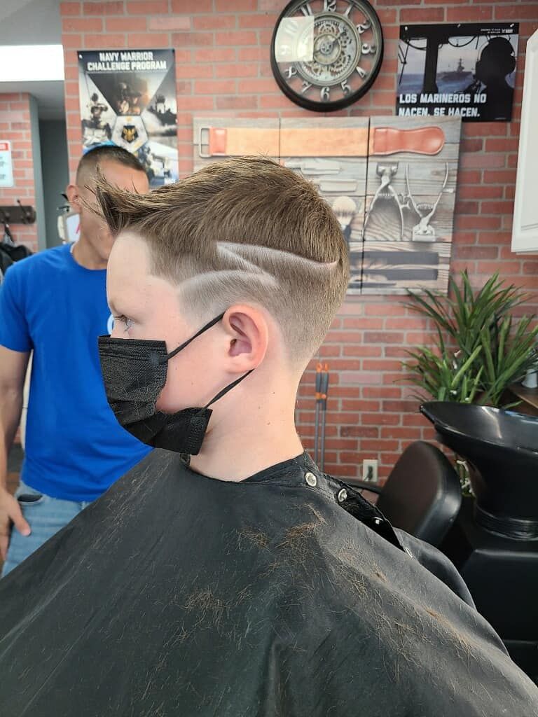 A young boy is getting his hair cut at a barber shop.