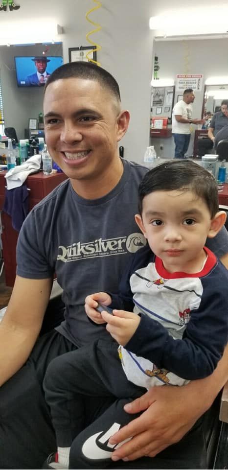 A young boy is getting his hair cut at a barber shop.