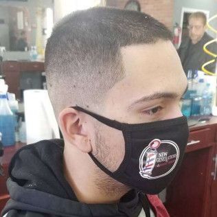 A man is wearing a face mask in a barber shop.