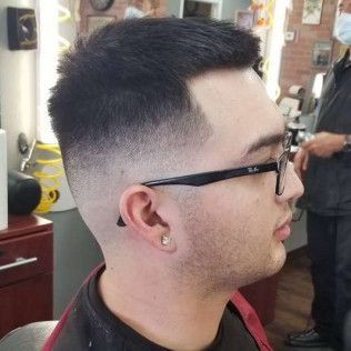 A man wearing glasses is getting his hair cut at a barber shop.