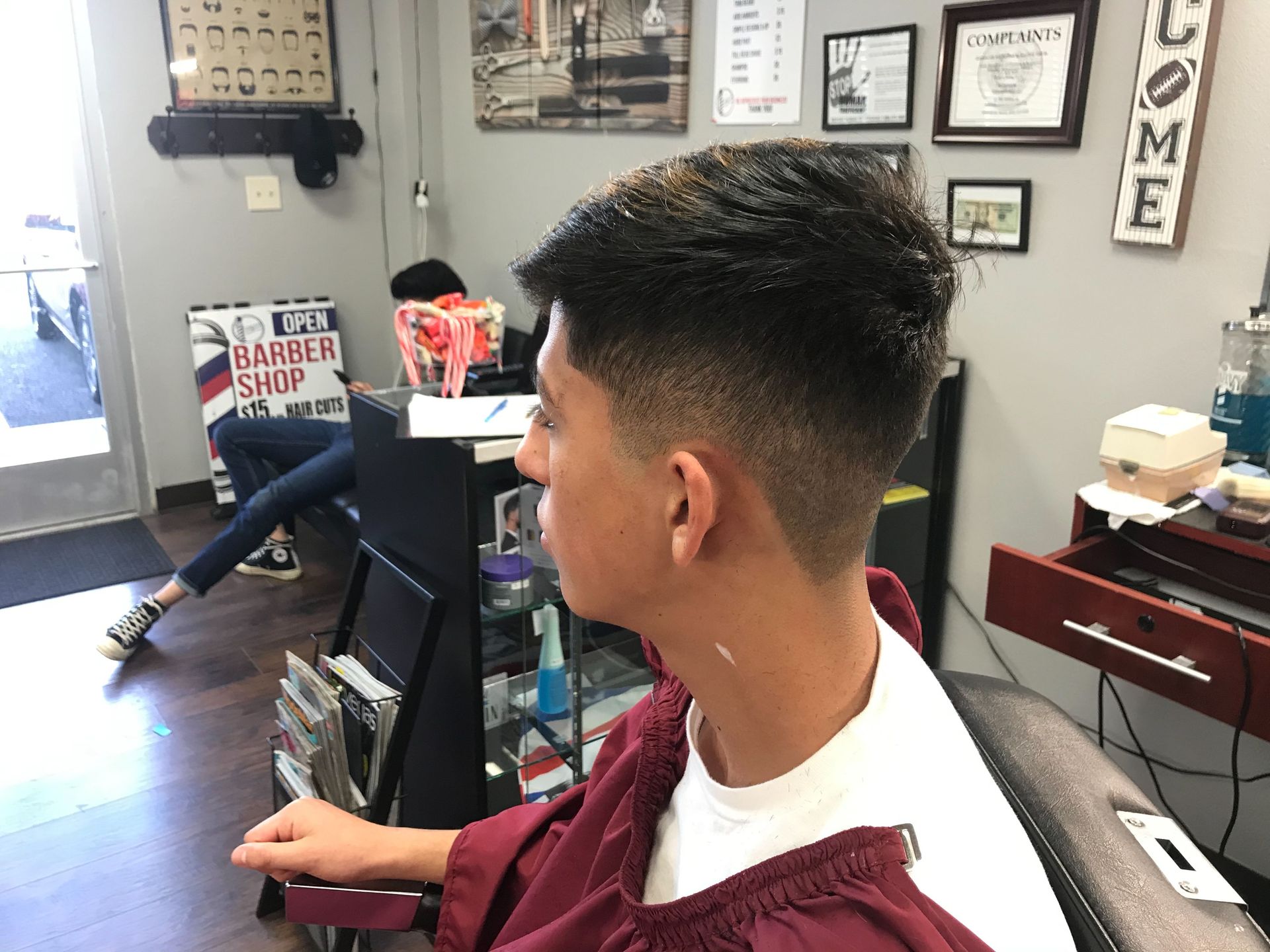 A man is getting his hair cut at a barber shop.