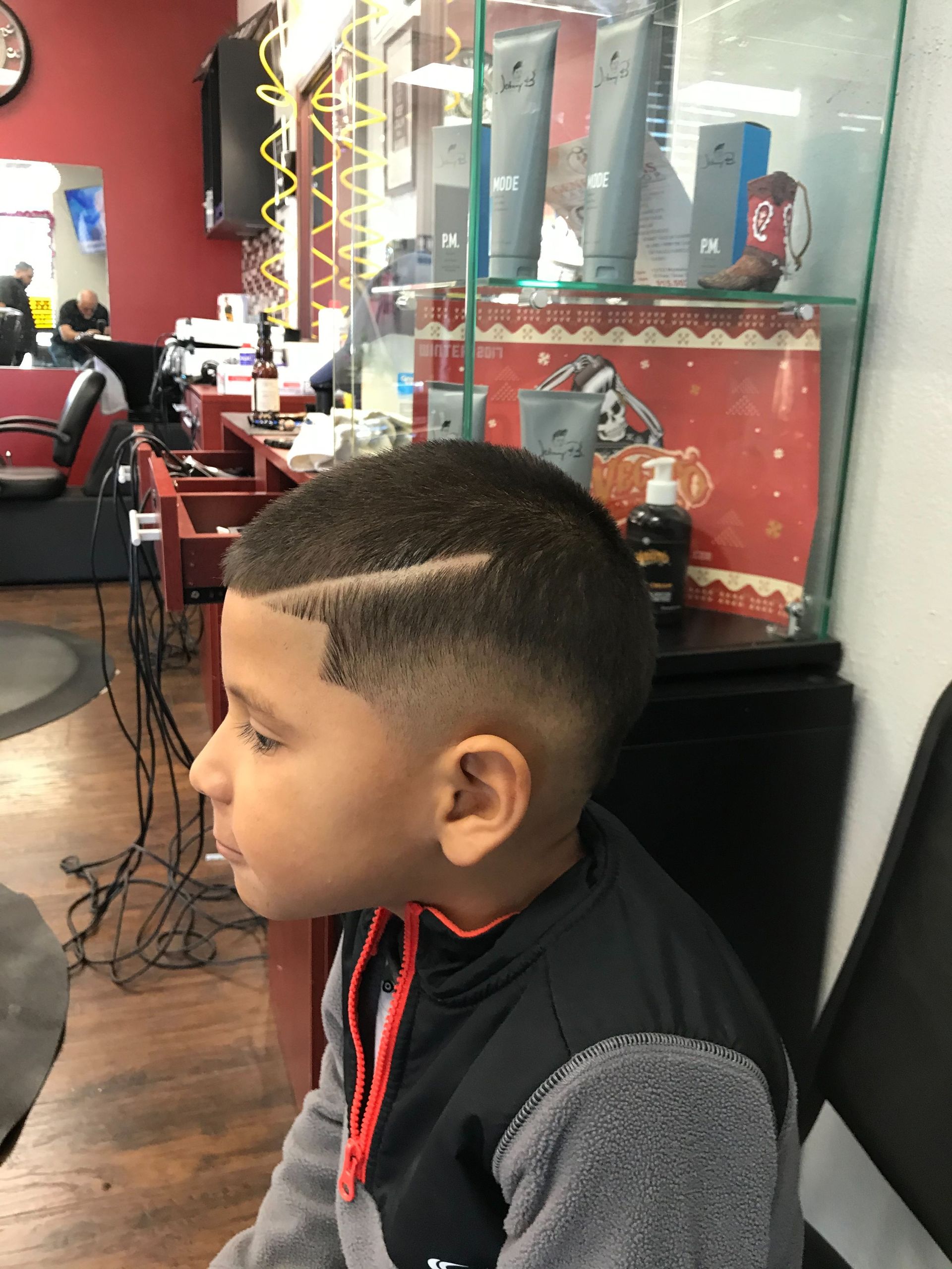 A young boy is getting his hair cut at a barber shop.