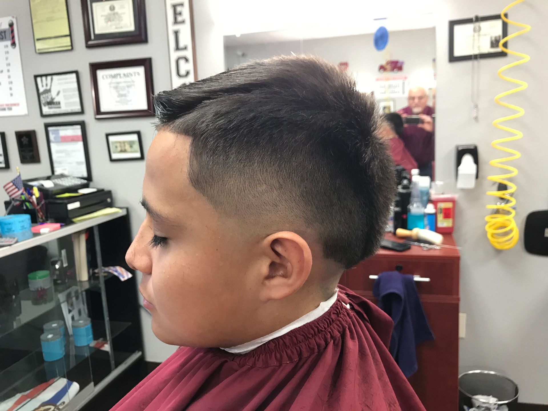 A young boy is getting his hair cut at a barber shop.