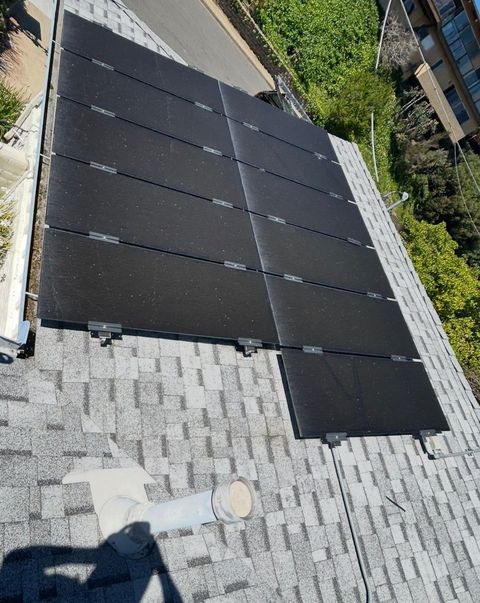 A high-angle view of solar panels installed on a sloped shingled residential roof.