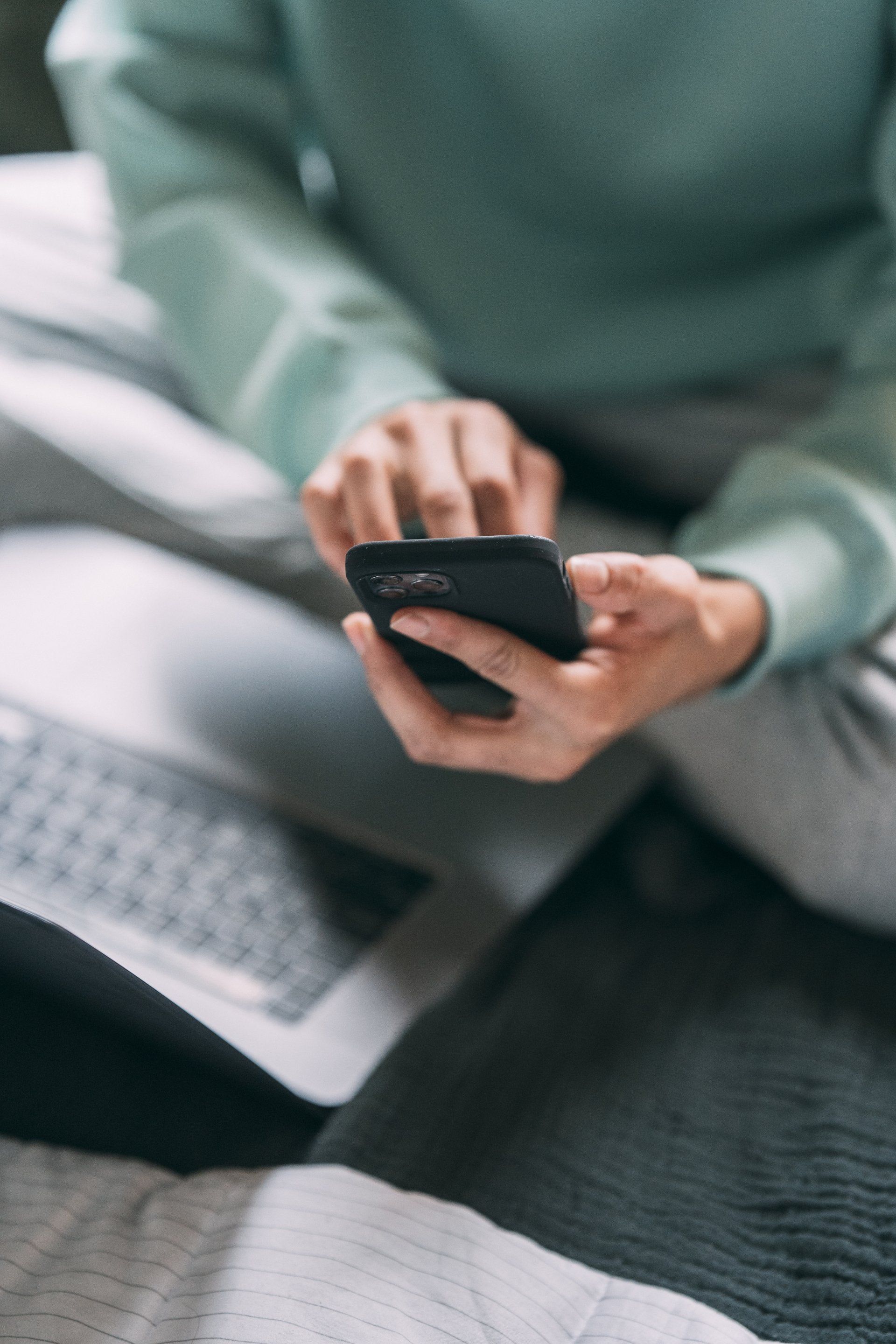 A person is sitting on the floor using a cell phone.