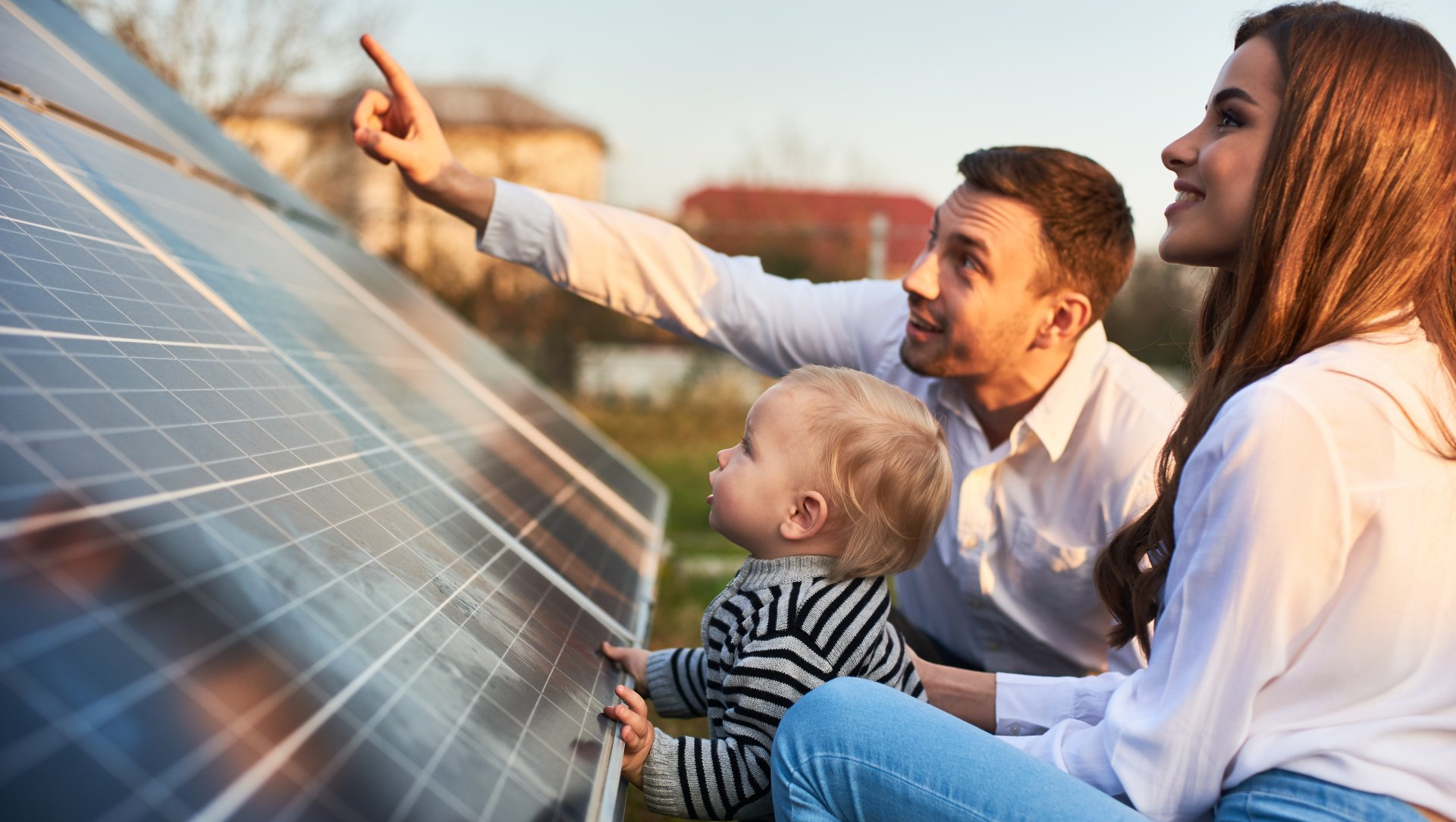A family is looking at a solar panel on the roof of their house.