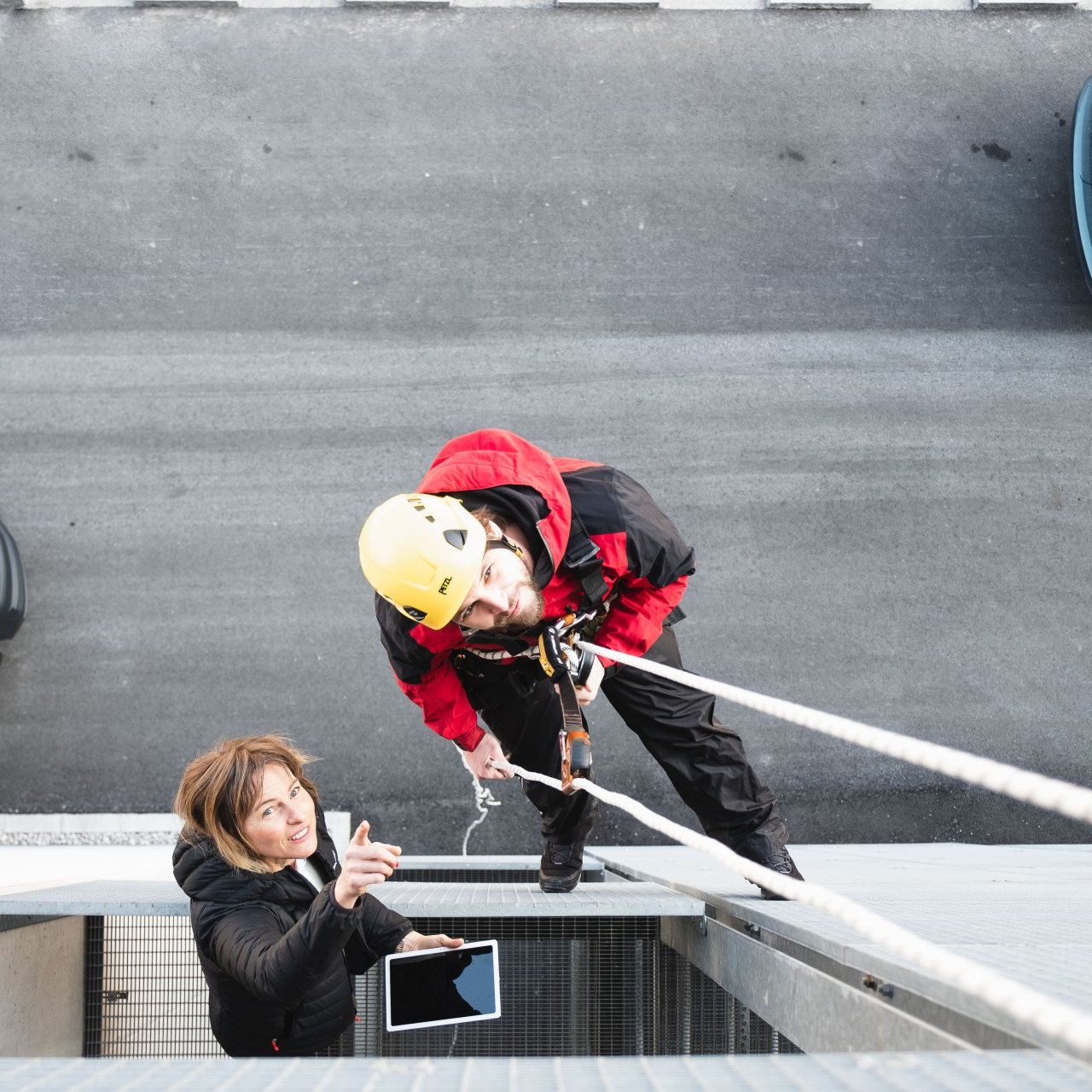 Mann, Frau, von oben, seilt sich ab, gelber Helm, Sicherheitsfachkraft (SFK)