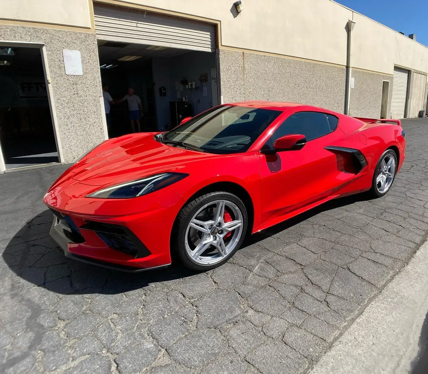 Red Dodge Challenger with black racing stripes parked in a garage.