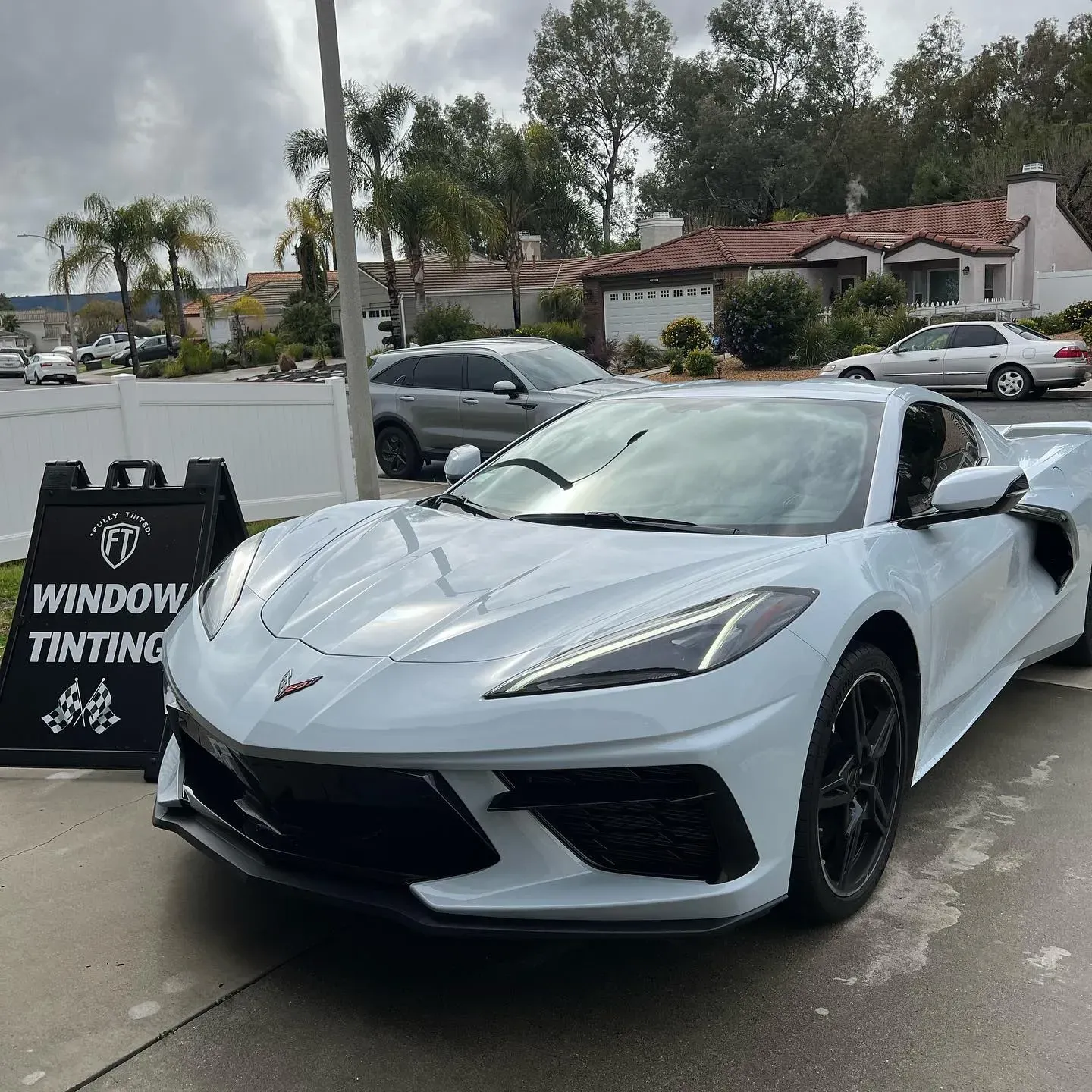 Black Corvette in a garage with hexagon-shaped lights. Garage has advertising posters hanging on the wall.