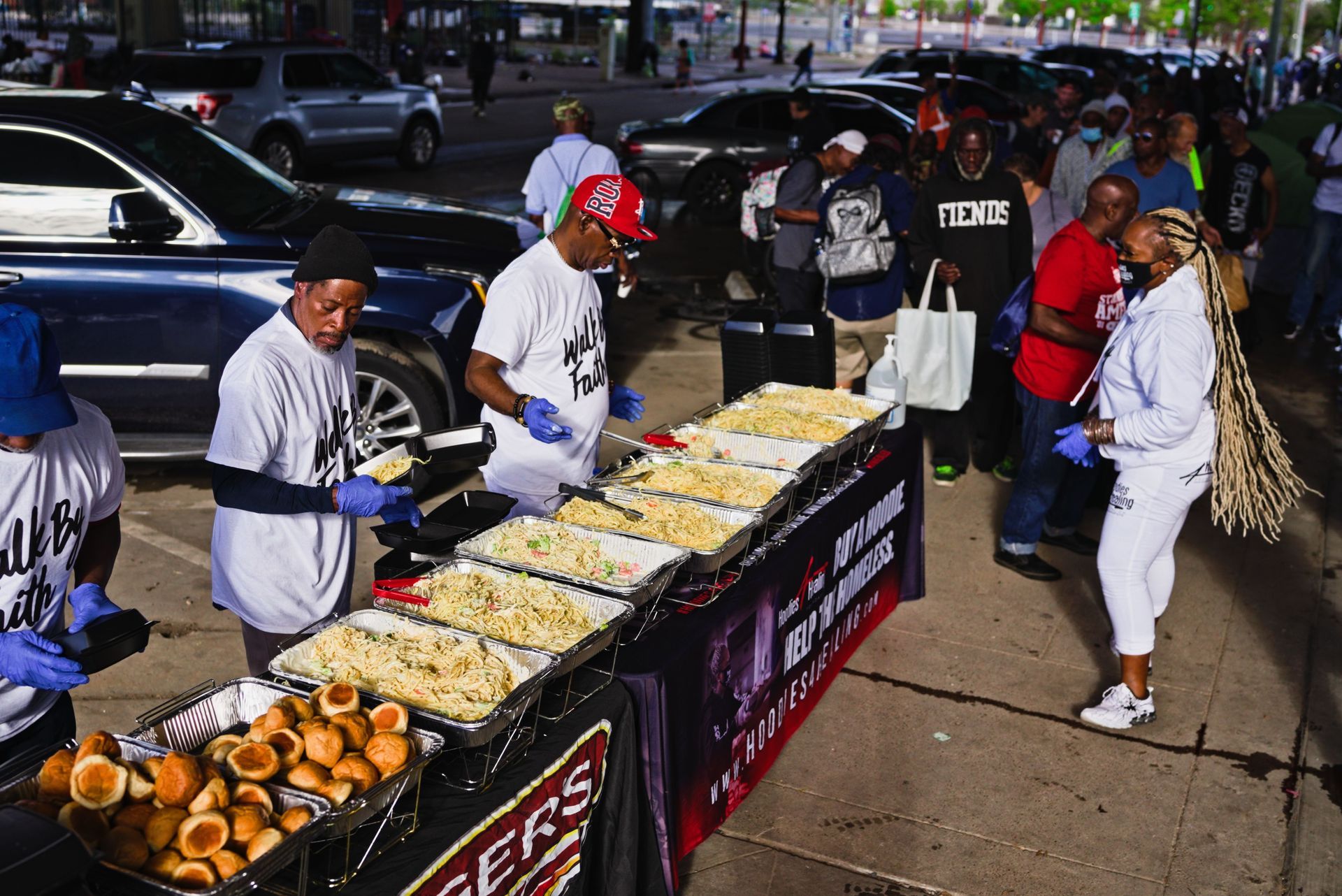A group of people are standing around a table filled with food.