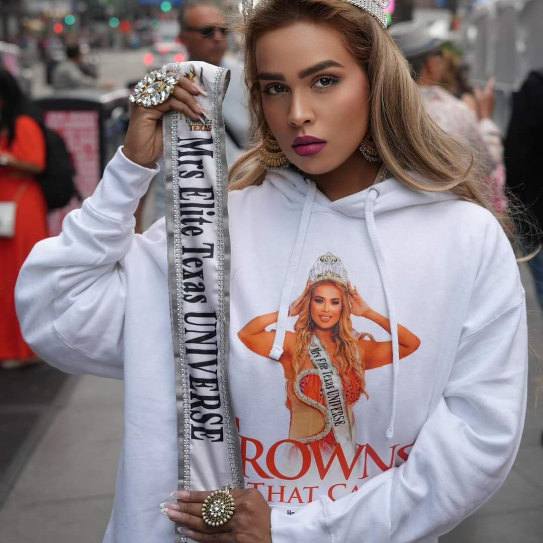 A woman holding a sash that says mrs elite 1st class universe