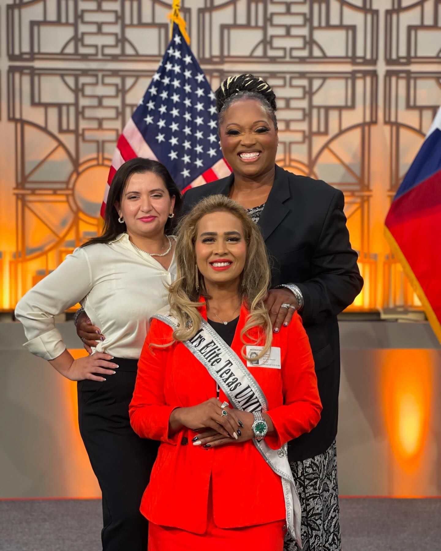 Three women are posing for a picture in front of an american flag