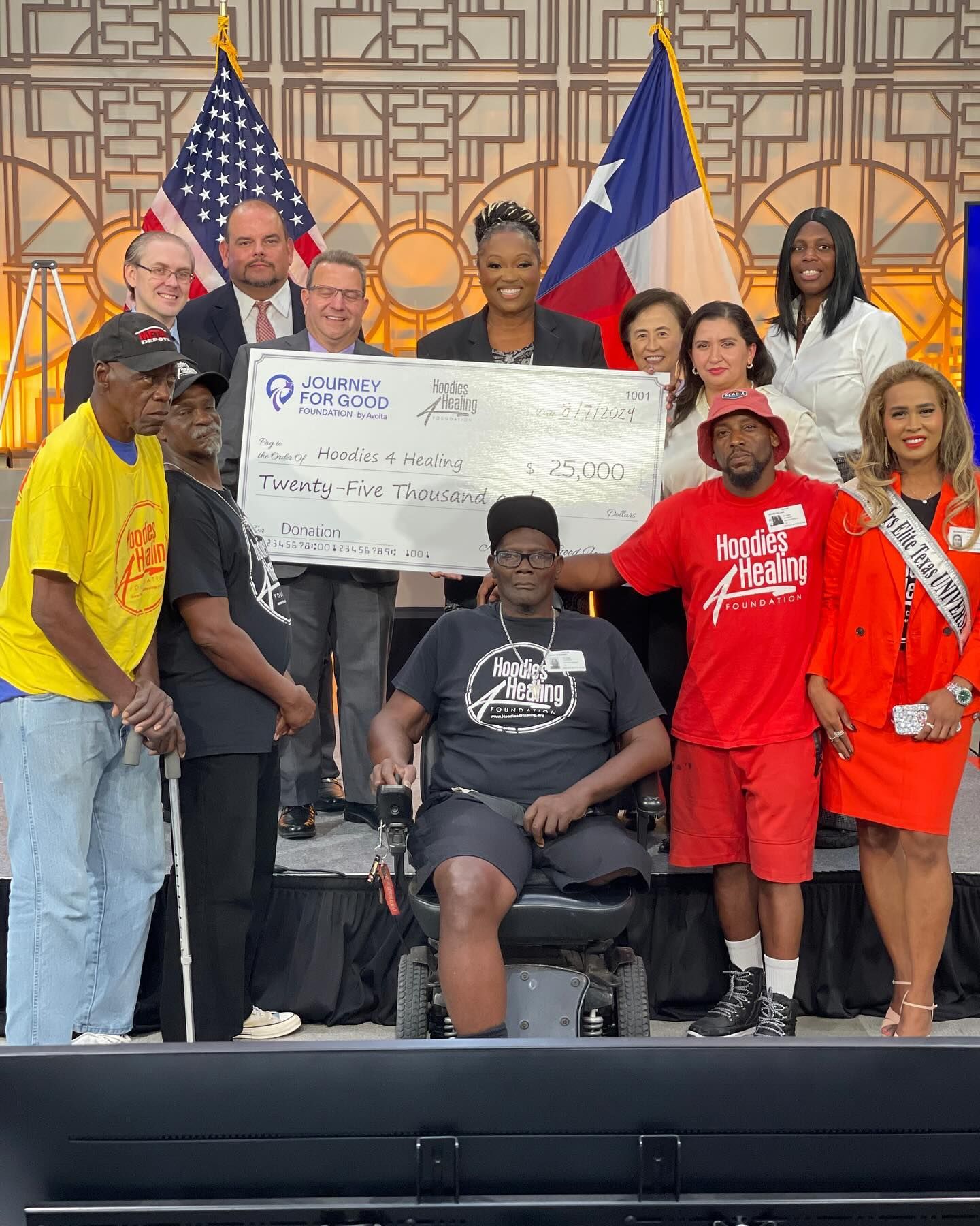 A group of people standing around a man in a wheelchair holding a large check.