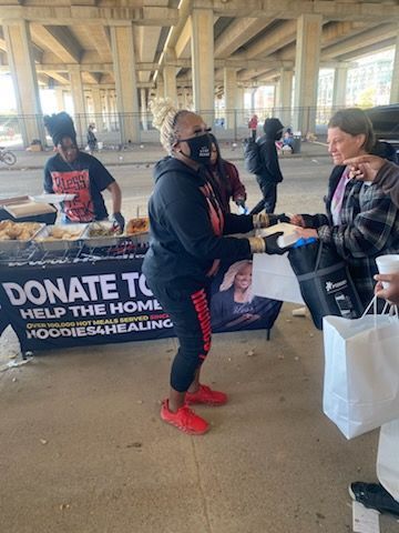 A woman in a white hoodie is standing in front of a van.