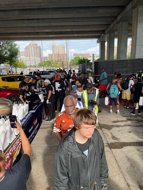 A group of people are standing in a line under a bridge.