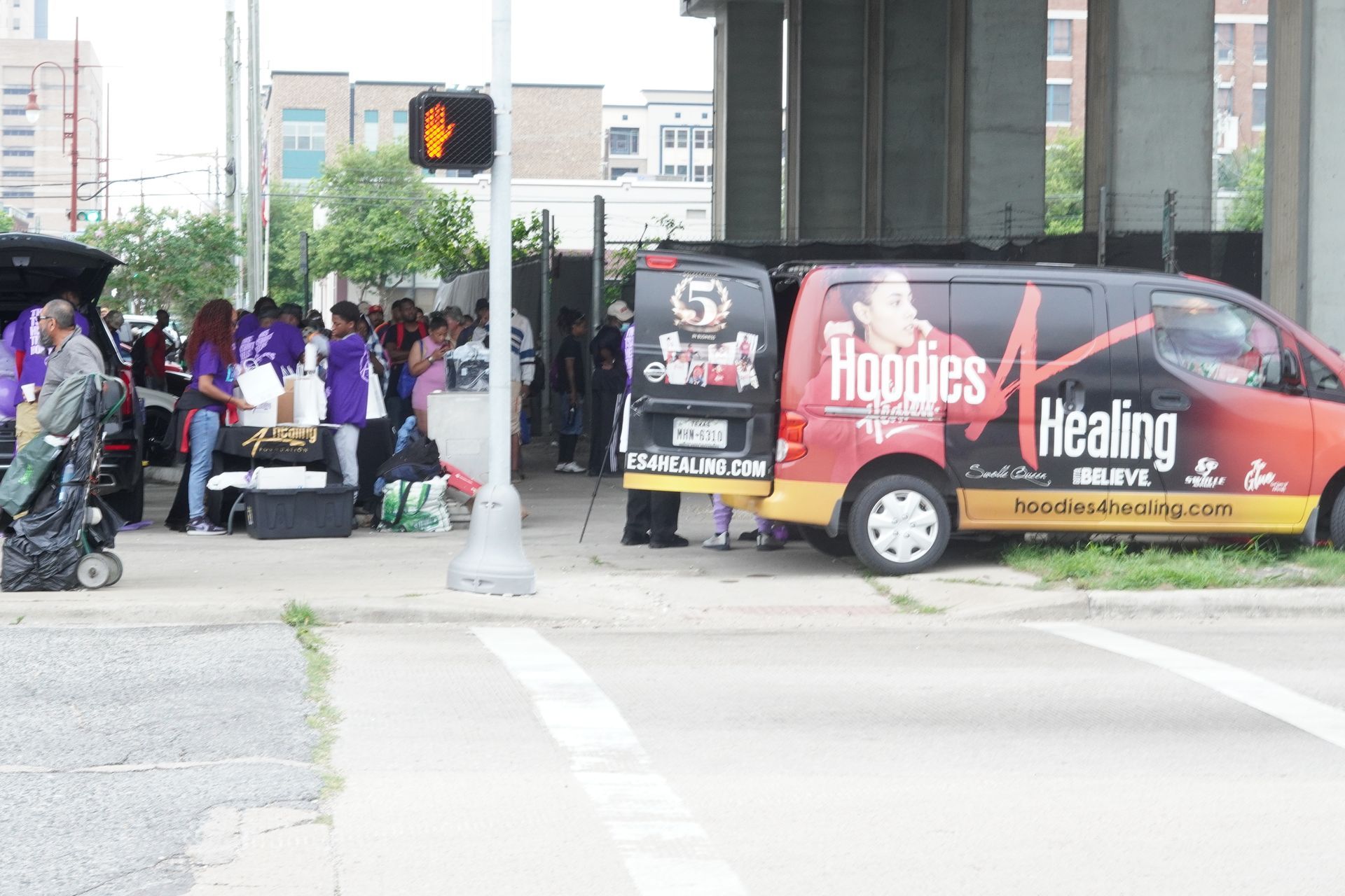A group of people are standing in front of a van that says healing.