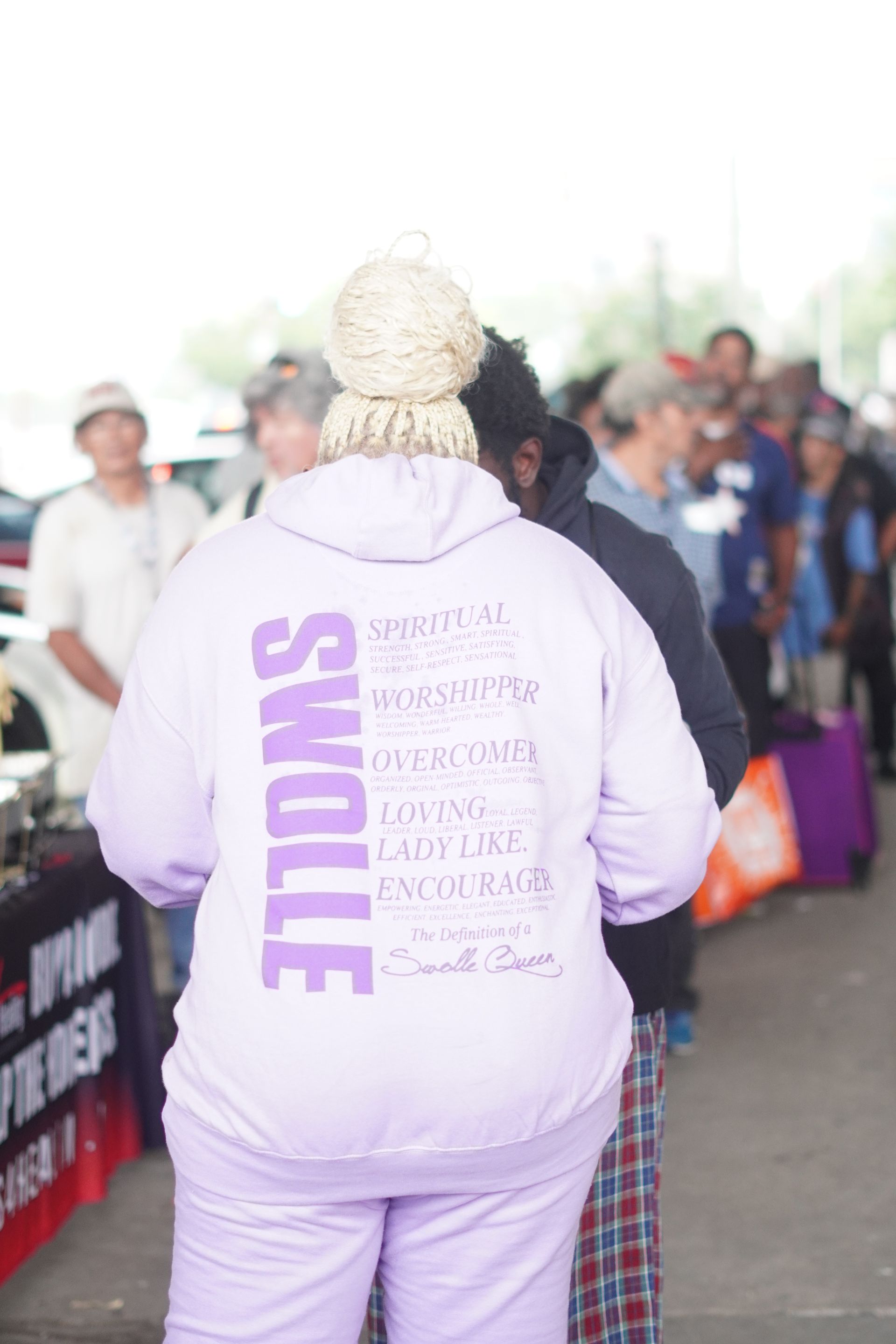A woman in a purple hoodie is standing in front of a crowd of people.