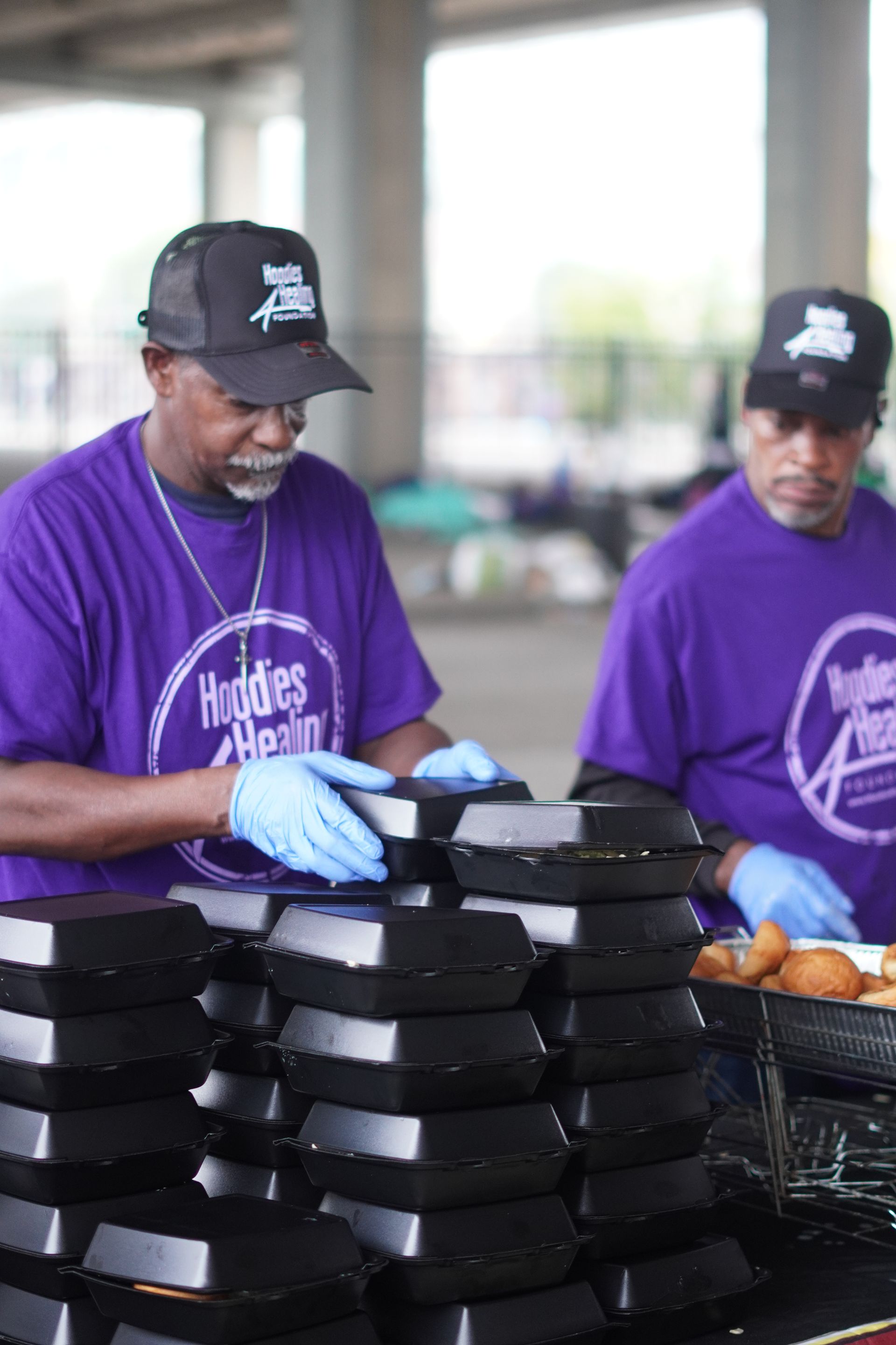 A man wearing a purple shirt that says hoodies on it