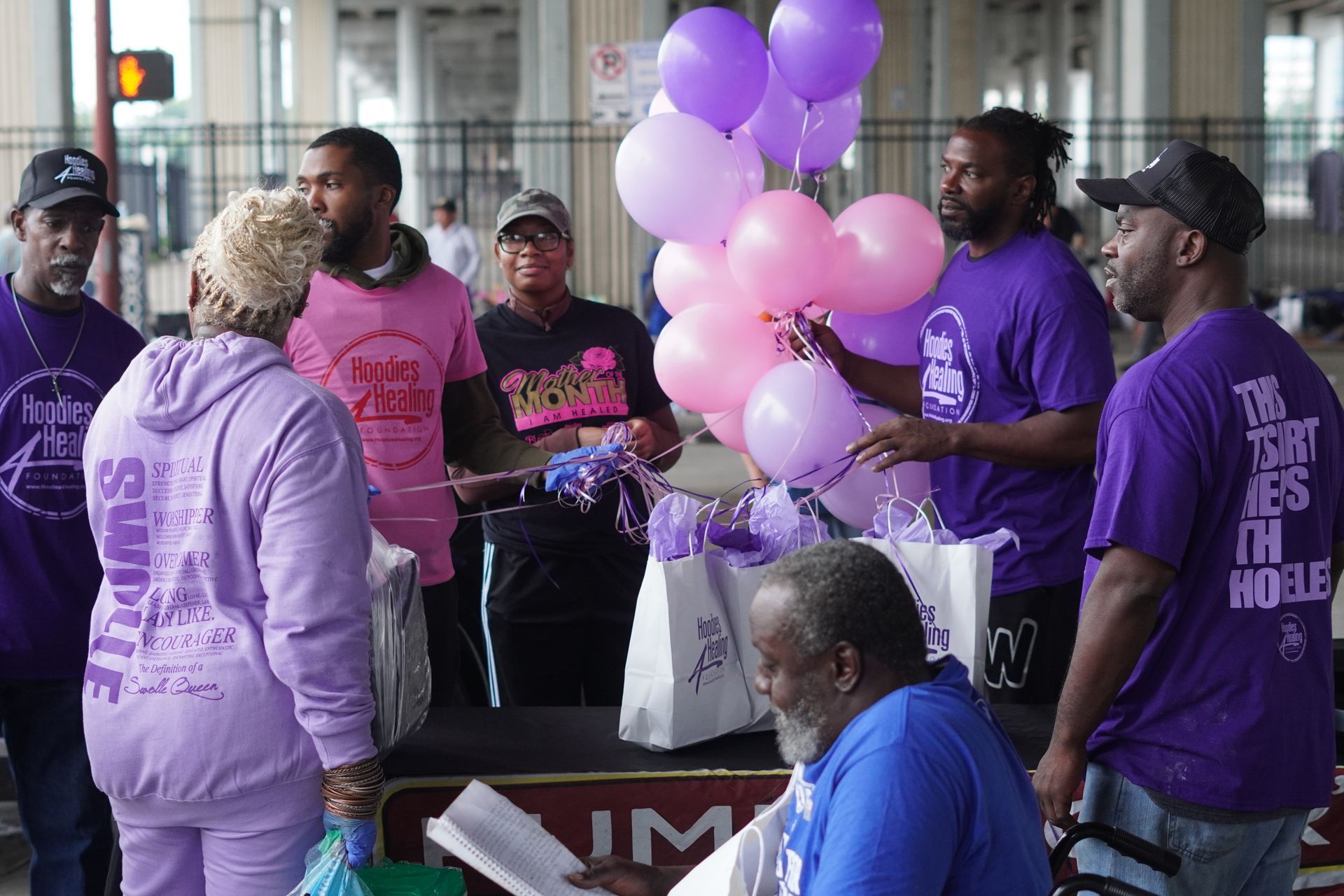 A group of people are standing around a table with purple balloons.