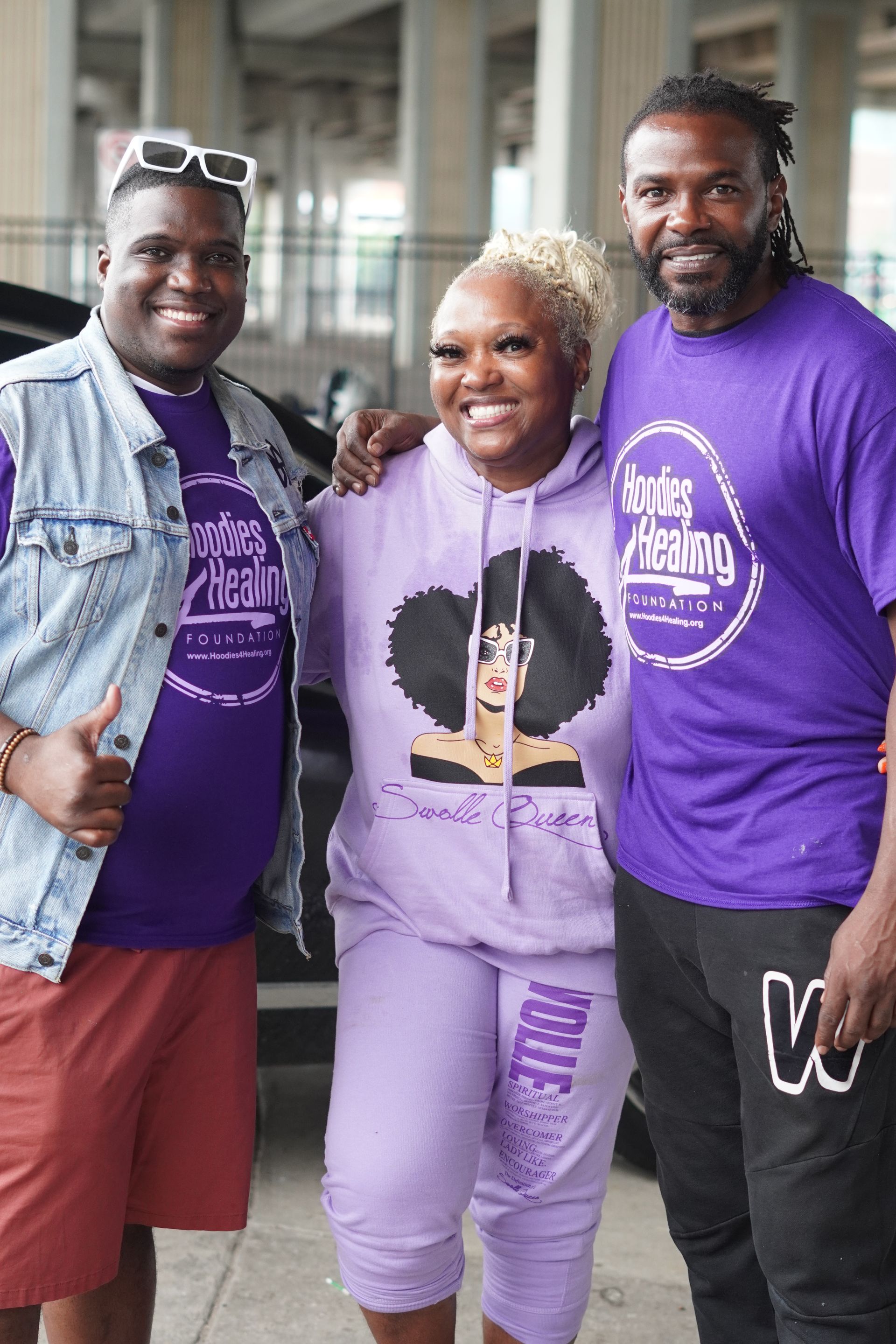 A woman in a purple hoodie is posing for a picture with two men.