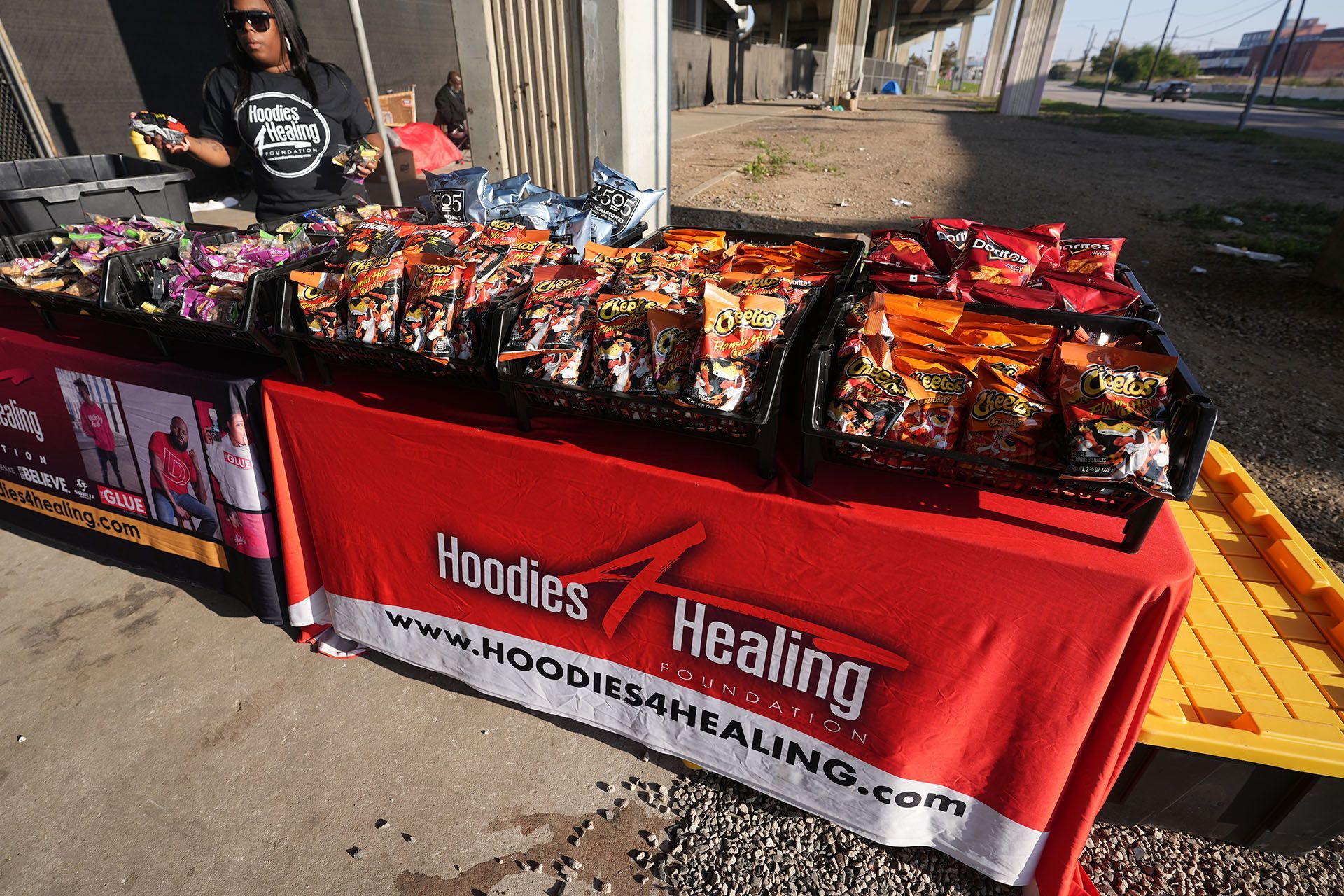 A man is standing behind a table that says hoodies healing